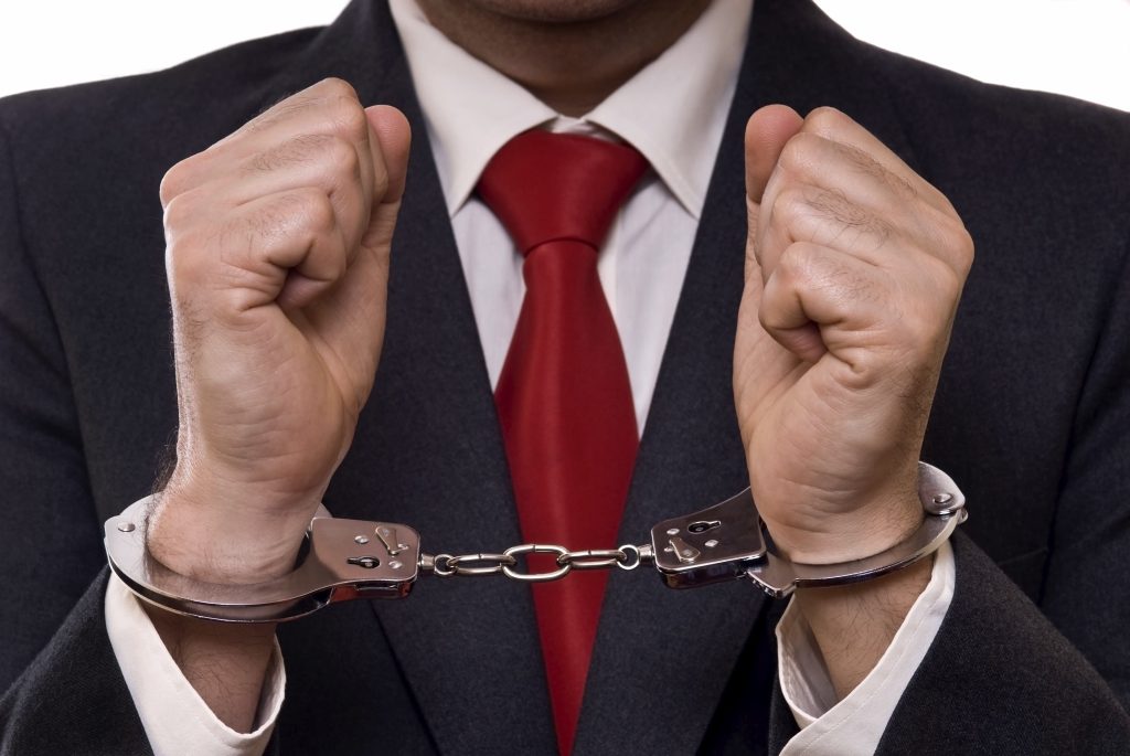 businessman in suit with hands in handcuffs